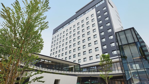 Een modern hotel met een meerlaags gebouw, grote ramen en een glazen gevel.