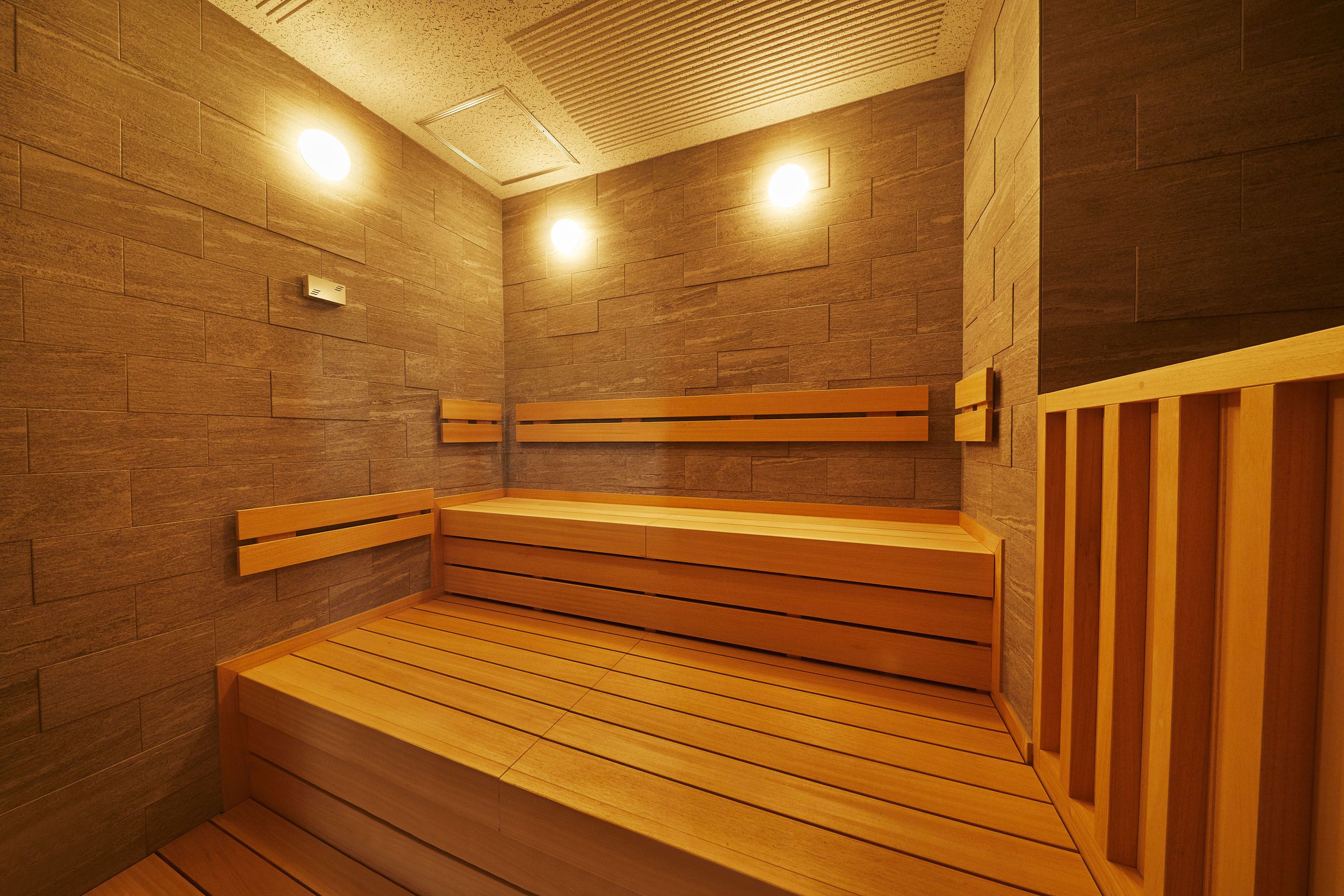 A sauna with wooden benches and walls, equipped with ceiling lights.
