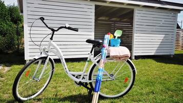 A white bicycle parked on grass in front of a white building with a garage door.
