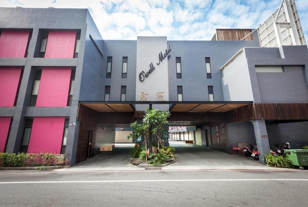 A hotel entrance with a modern design, featuring a prominent sign and a covered driveway.
