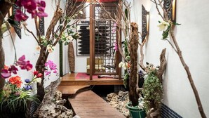 Un estrecho sendero de madera que conduce a una habitación tradicional japonesa con puertas correderas y una pequeña plataforma de madera.