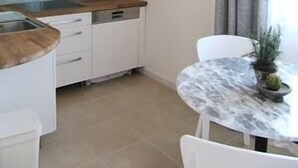Una cocina moderna con armarios blancos, encimera de madera y una pequeña mesa de comedor con sillas.