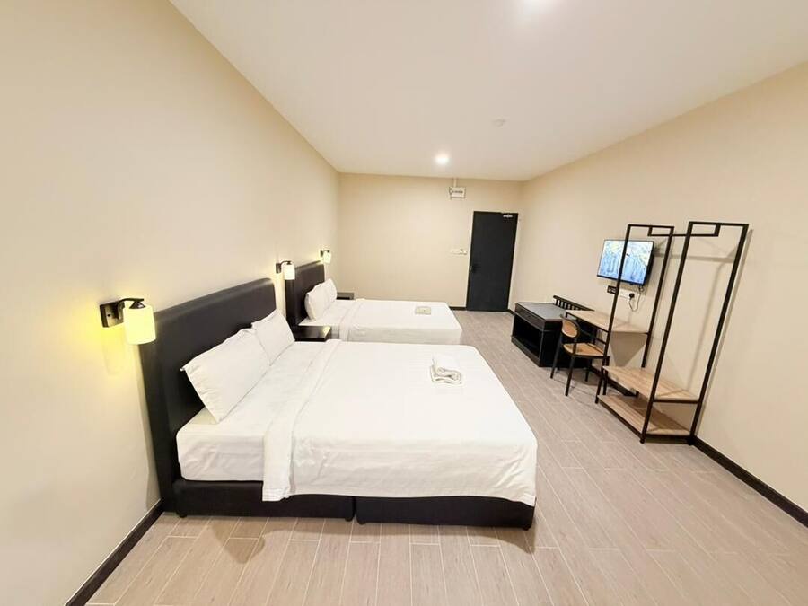 Habitación de hotel con dos camas, un escritorio, una silla, un televisor y un armario.