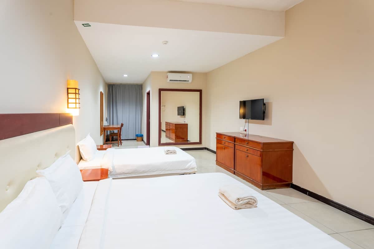 A hotel room with two beds, a wooden dresser, a television, and a desk with a chair.