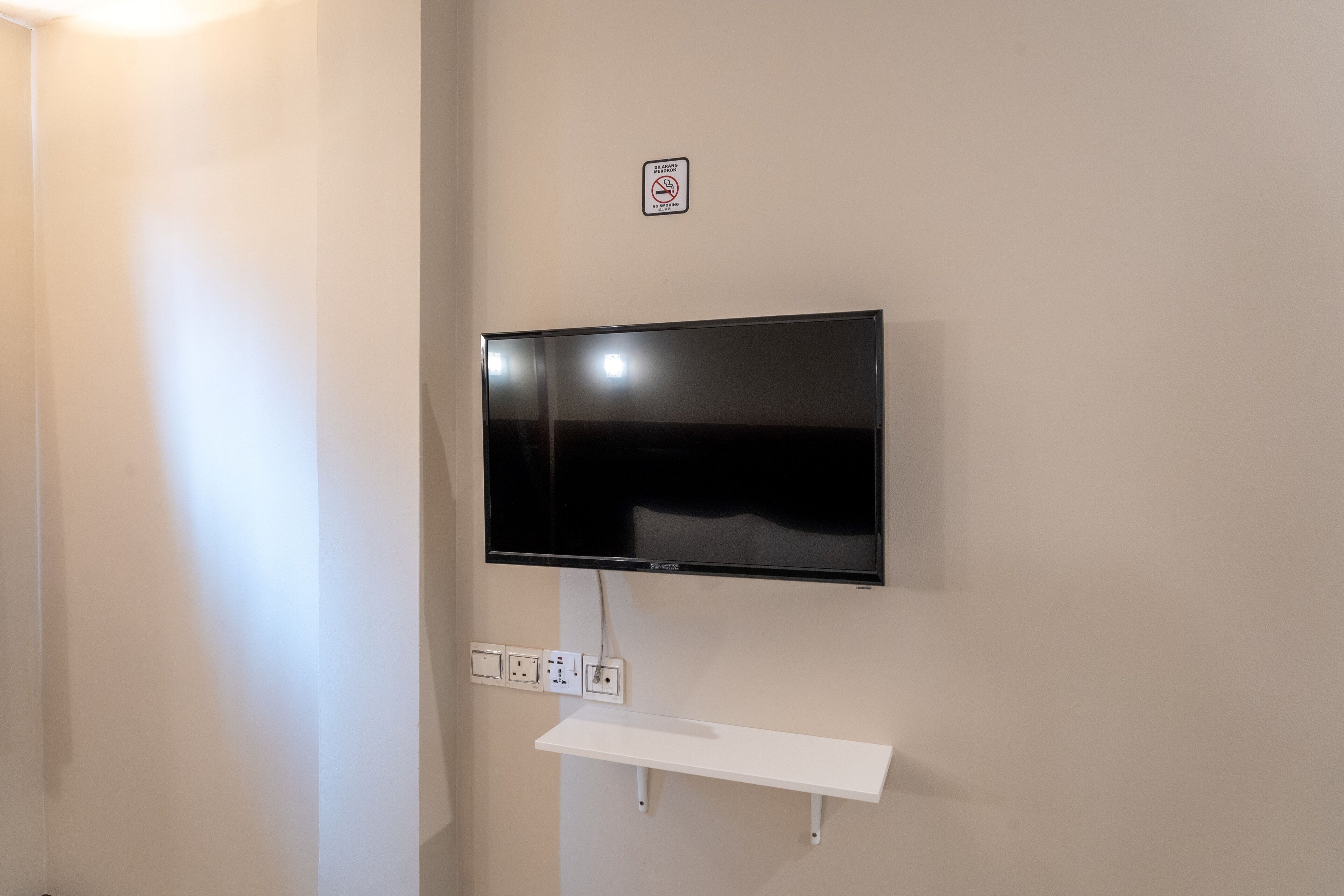A flat-screen TV mounted on a wall with a power outlet below it.