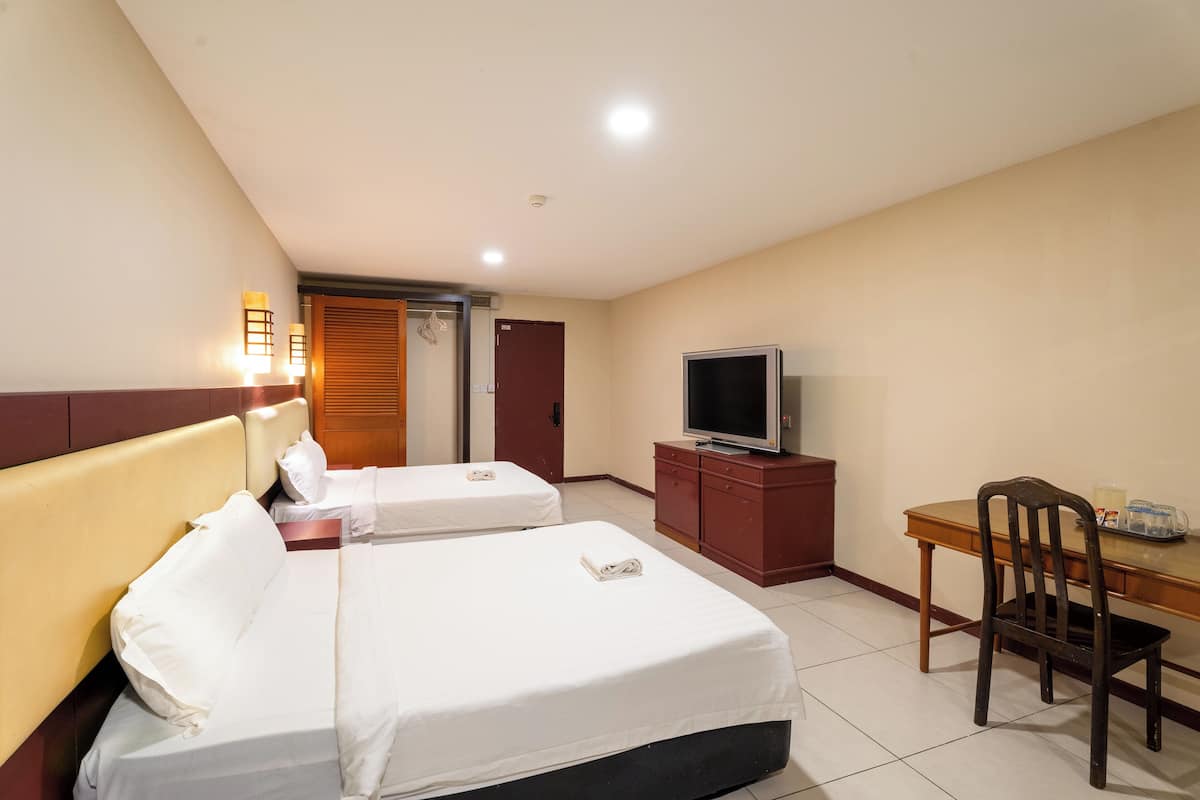 A hotel room with two beds, a TV, a desk, and a chair.