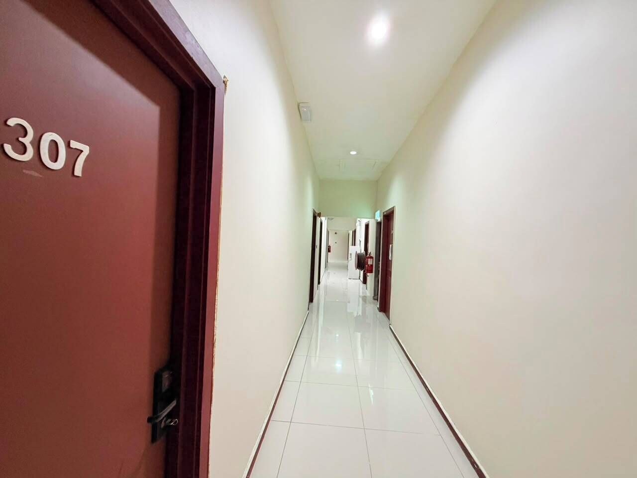 A hotel corridor with a clean, tiled floor and doors numbered 307.
