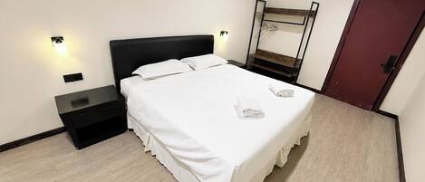A hotel room with a bed, bedside tables, a wardrobe, and a mirror.