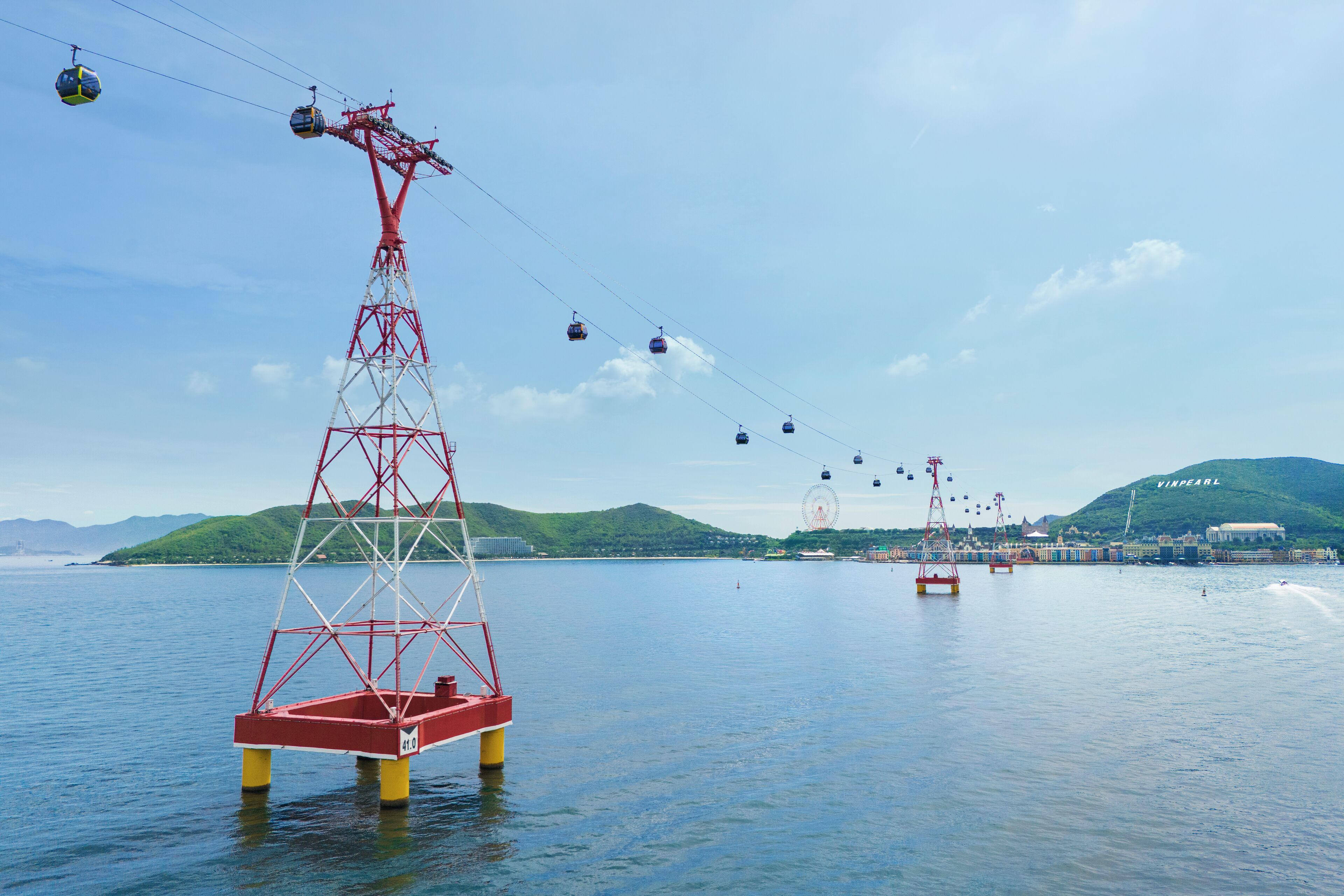 A cable car system over a body of water with a mountainous backdrop.