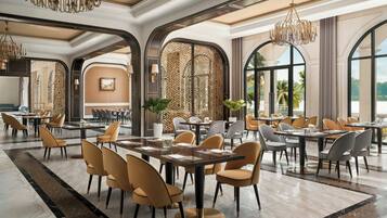 Un comedor amplio con techos altos, candelabros y ventanas grandes que ofrecen vistas al exterior.