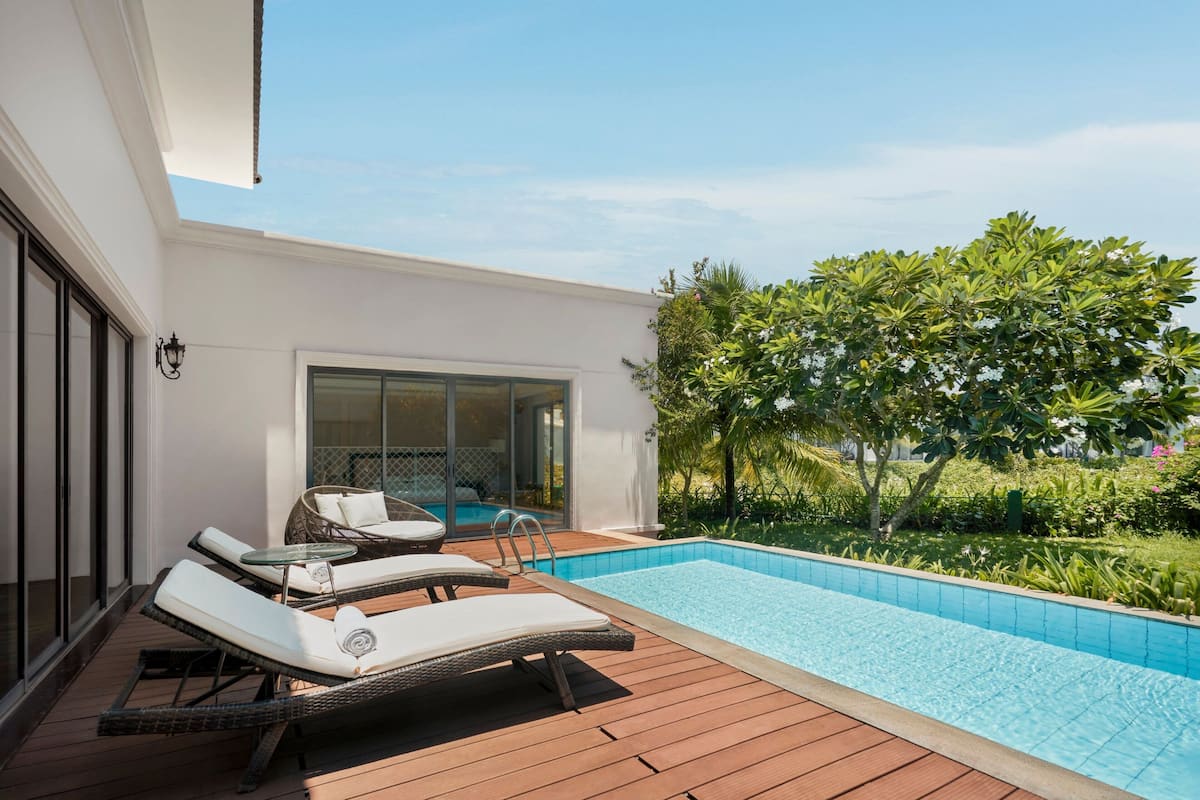Un área de piscina moderna al aire libre con sillones de descanso y una terraza de madera.