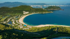 Une station balnéaire située sur la côte, dotée d’une plage, d’un grand bâtiment et d’un port de plaisance.