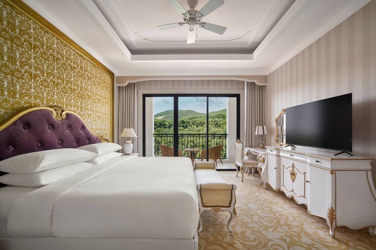 Una lujosa habitación de hotel con una cama grande, televisión, balcón y vistas panorámicas, además de una decoración elegante.