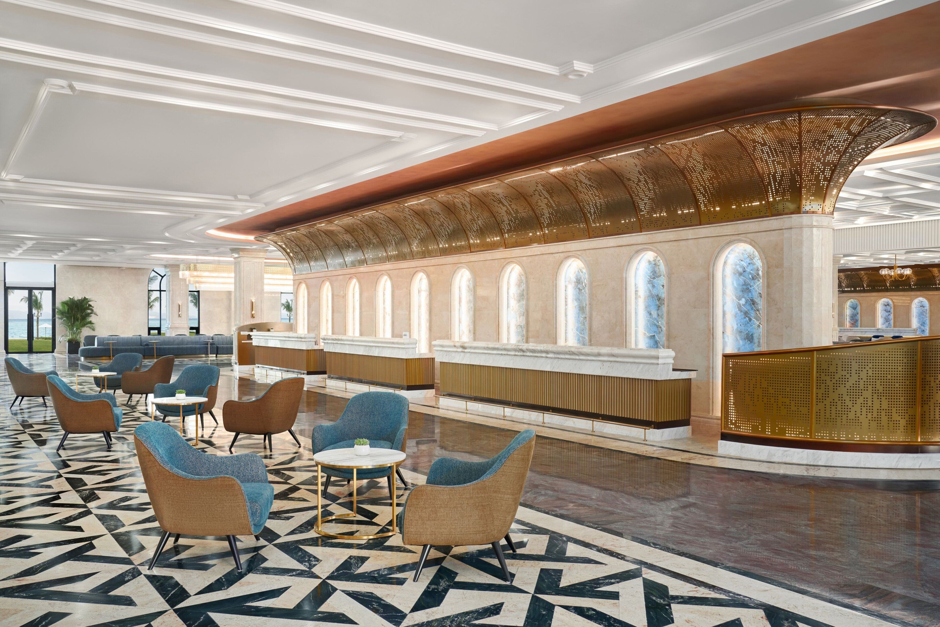 A spacious lobby with a reception desk, seating area, and a patterned floor.