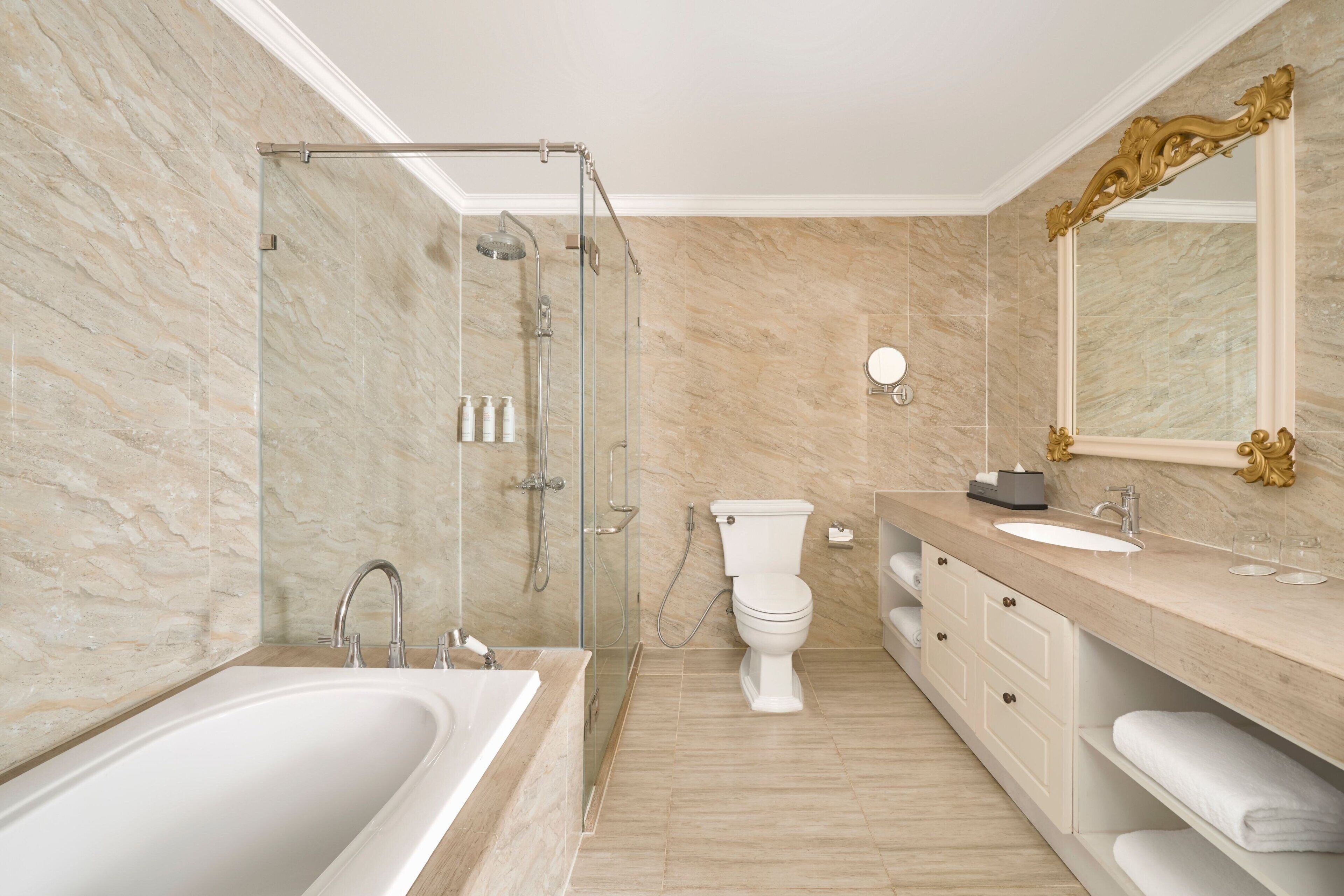 A modern bathroom with a glass-enclosed shower, a white bathtub, a toilet, and a vanity with a mirror and sink.
