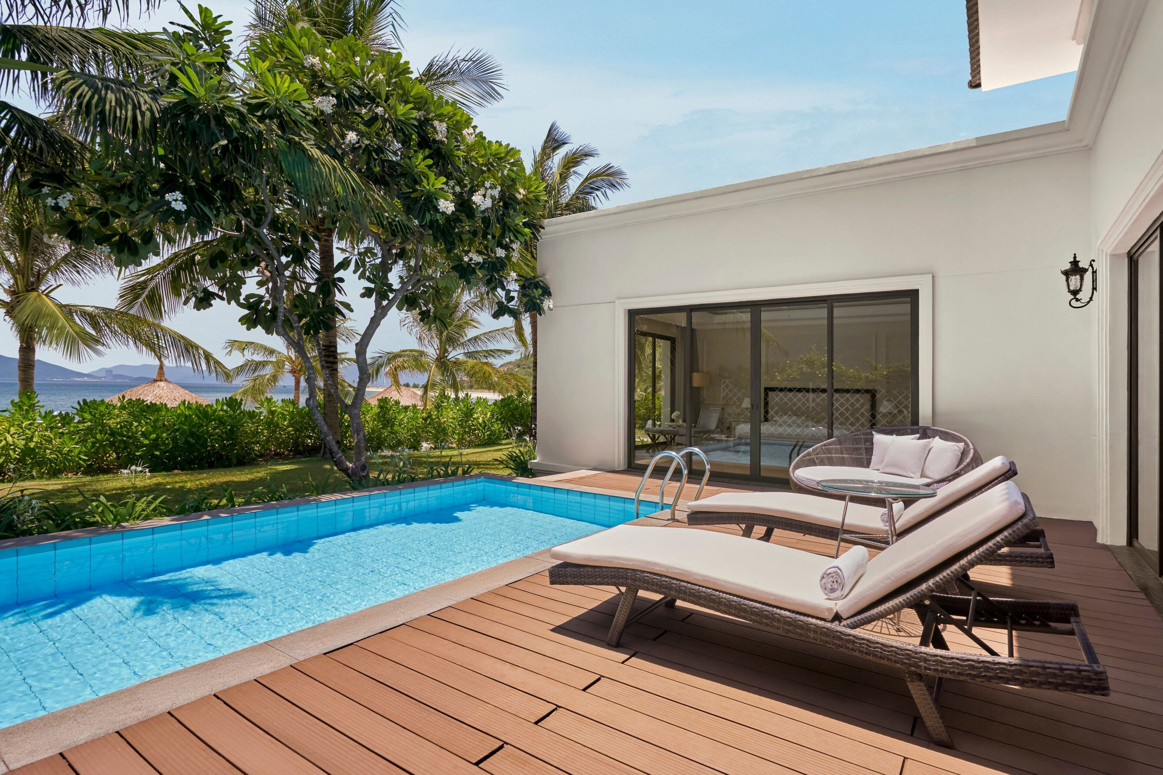 A poolside area with lounge chairs and a clear view of the ocean.