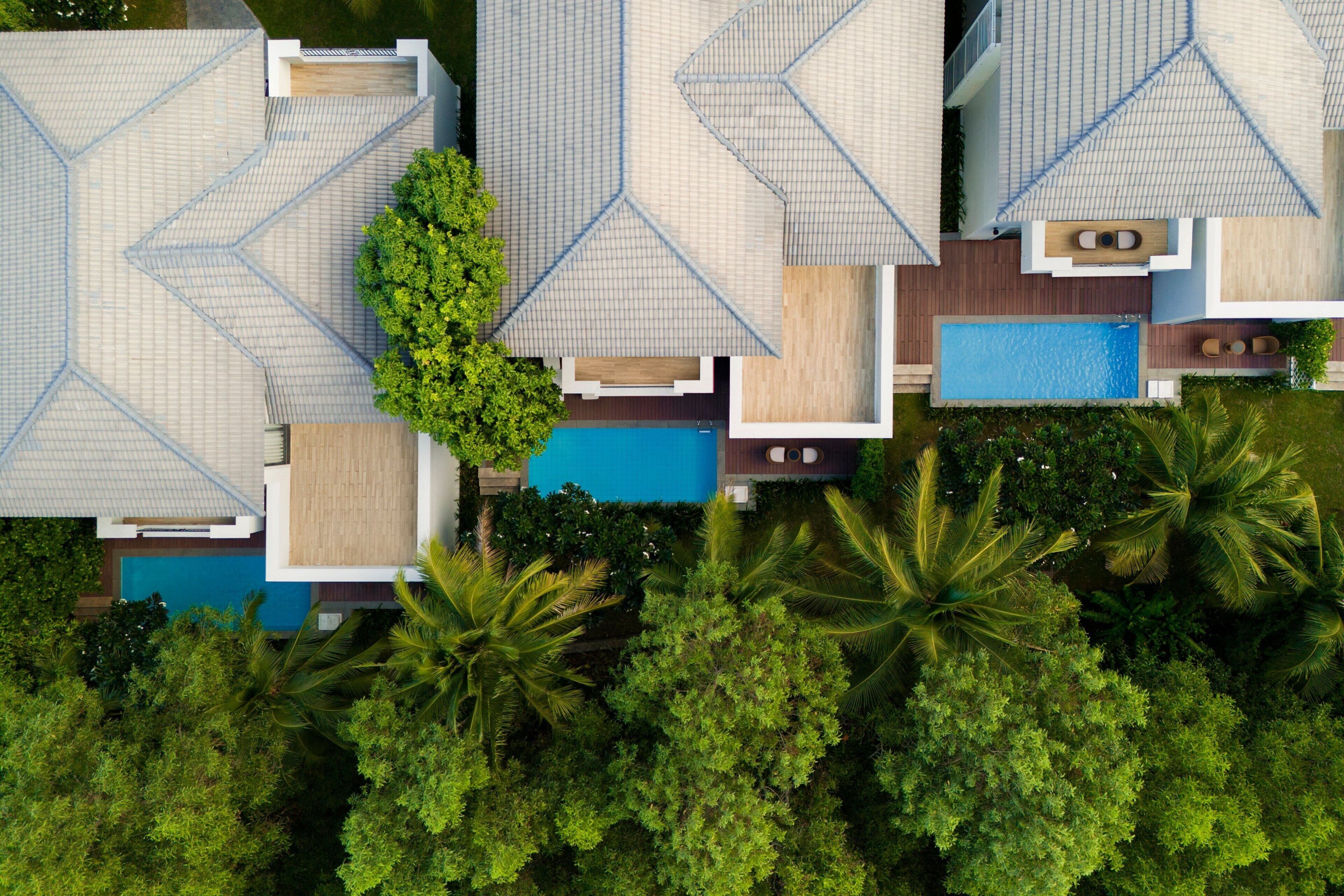 An aerial view of a resort with multiple buildings, a swimming pool, and lush greenery.