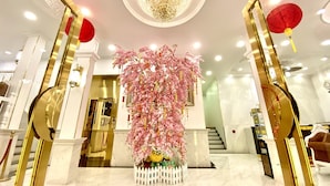 Un hall d’entrée doté d’un sol en marbre, d’un grand lustre et d’une composition florale décorative aux tons roses.