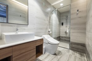 A modern bathroom with a large sink, toilet, and glass shower enclosure. - Grange Inn (Taitung)