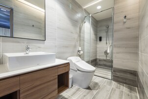 Un baño moderno con un lavamanos grande, inodoro y cabina de ducha de vidrio.