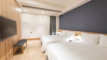 A hotel room with two beds, a flat-screen TV, a bench, and a nightstand with a lamp.