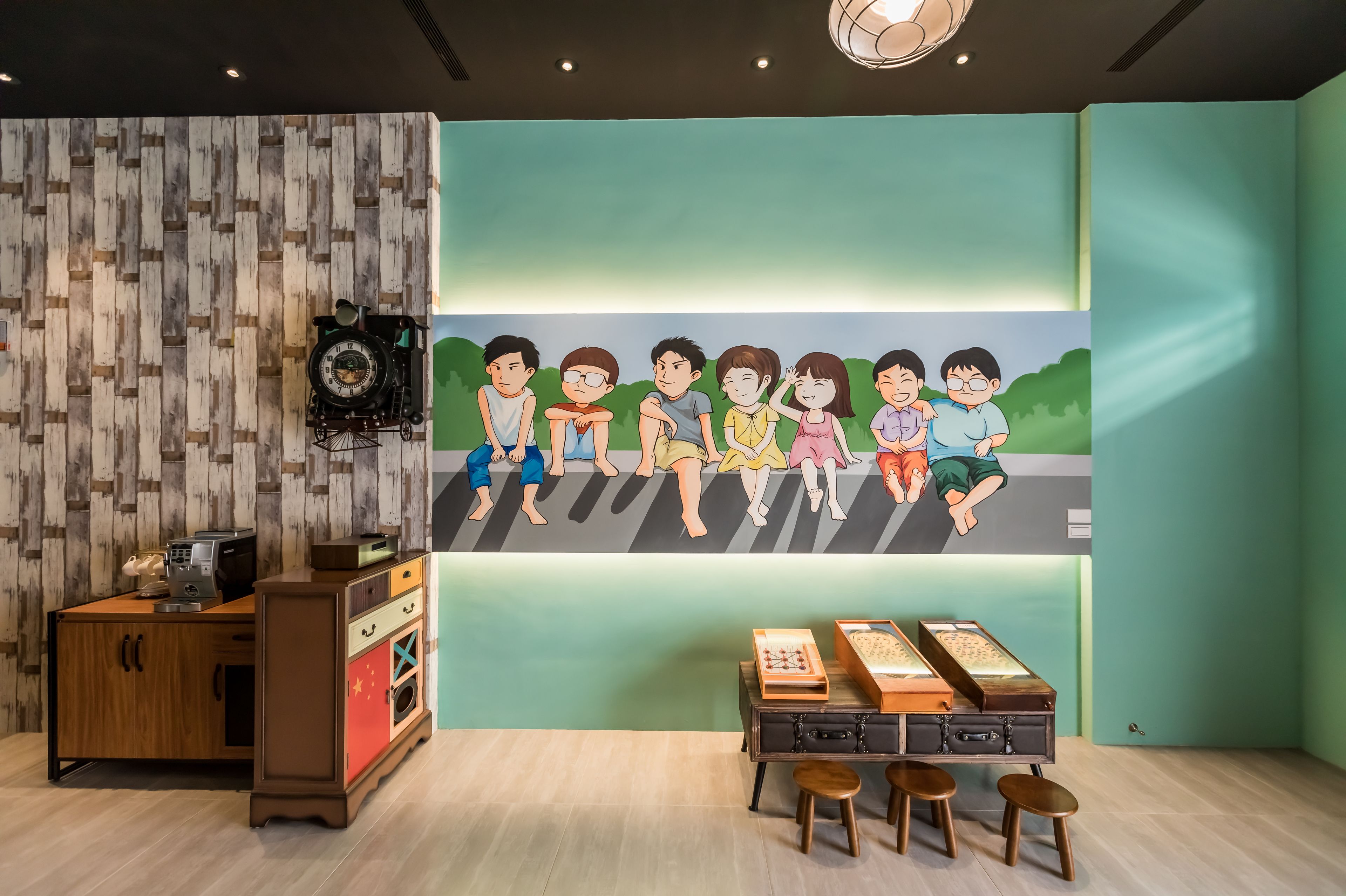 A room with a wooden wall, a desk with a computer, a clock, and a shelf with books.