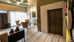 Un interior moderno con piso de madera, un comedor con sillas, una mesa con osos de peluche y un elevador instalado en la pared.