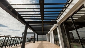Un espacio exterior cubierto con vistas al horizonte de la ciudad, que presenta un diseño arquitectónico moderno con vigas de metal y puertas de vidrio.