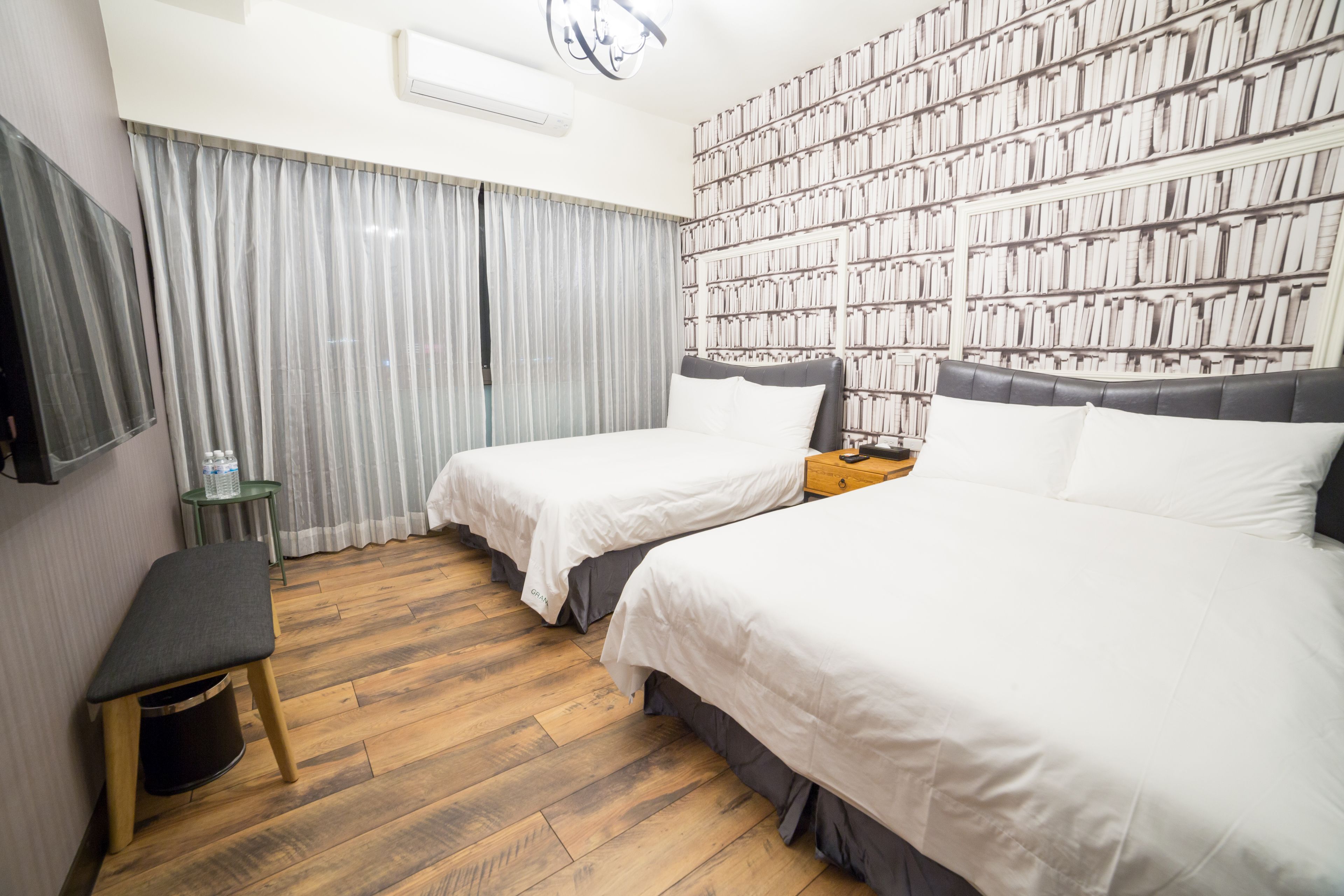 Een hotelkamer met twee bedden, een boekenplank, een tafeltje en een bank.