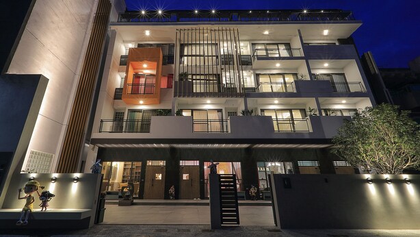 Un edificio de varios pisos con un diseño moderno, que cuenta con balcones y grandes ventanales.