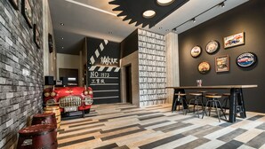Una zona de bar con suelo a cuadros, taburetes y una exhibición de coches antiguos.