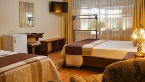 Een hotelkamer met twee bedden, een bureau, een stoel, een televisie en een lamp.