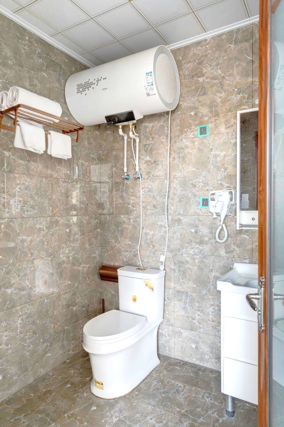 Une salle de bain moderne avec un sol en marbre, des toilettes blanches, un lavabo et un porte-serviettes.