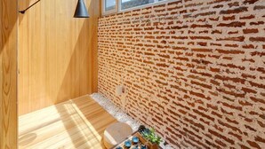 Une pièce baignée de lumière naturelle, avec un plancher en bois, un mur en briques et une lucarne.