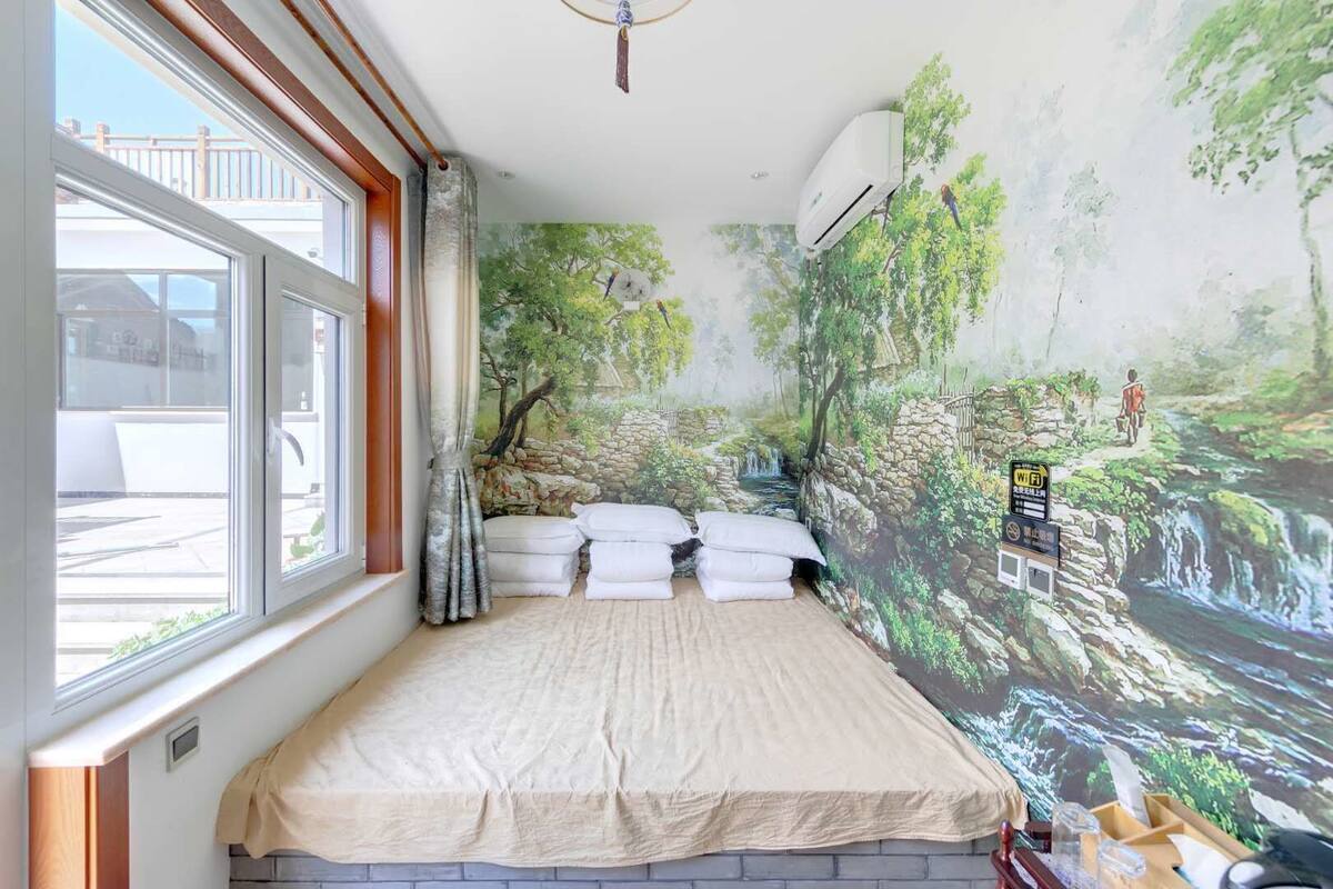 Een slaapkamer met een bed, een raam, een muurschildering en een airconditioning.