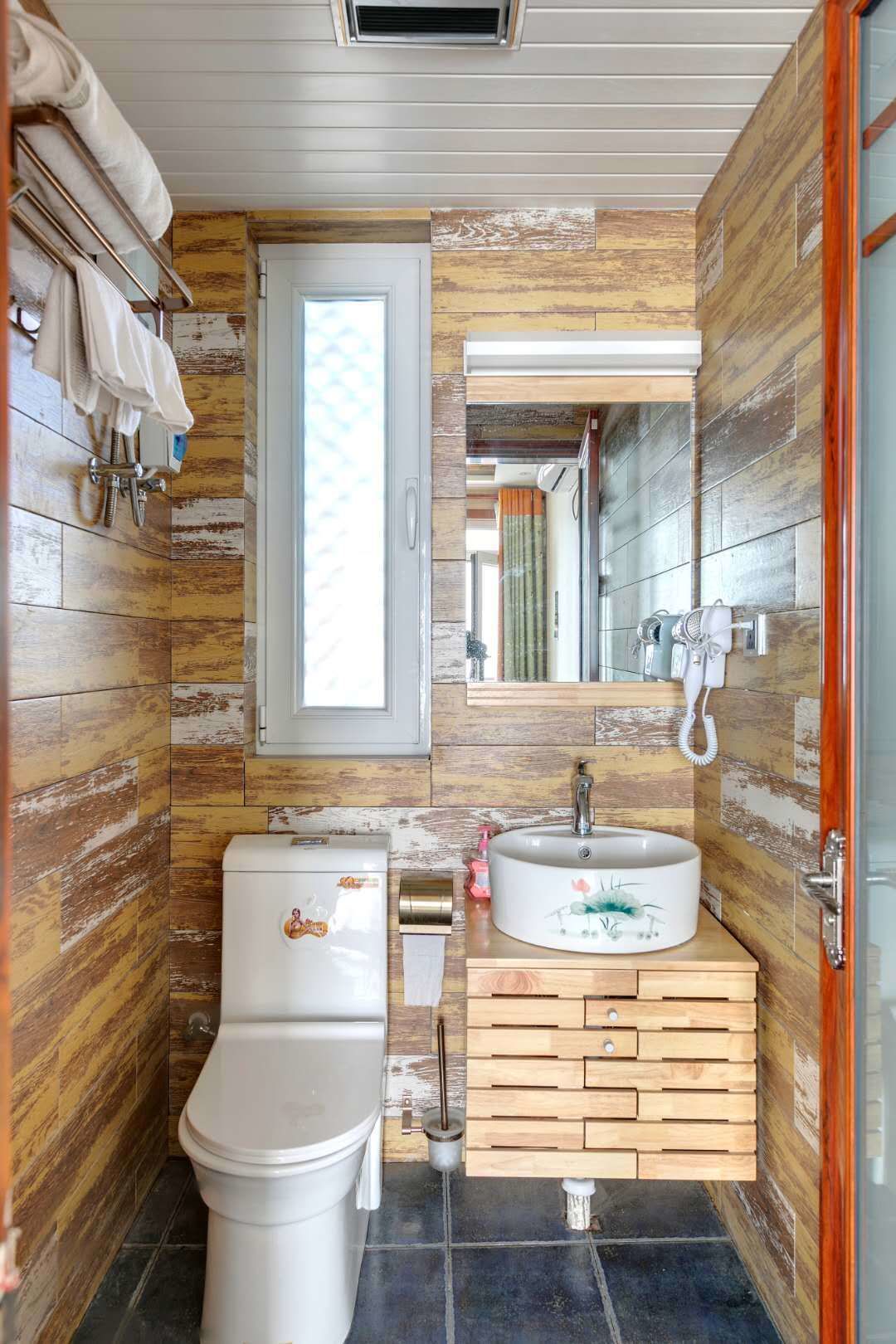 A compact bathroom with a toilet, sink, and wooden wall paneling.