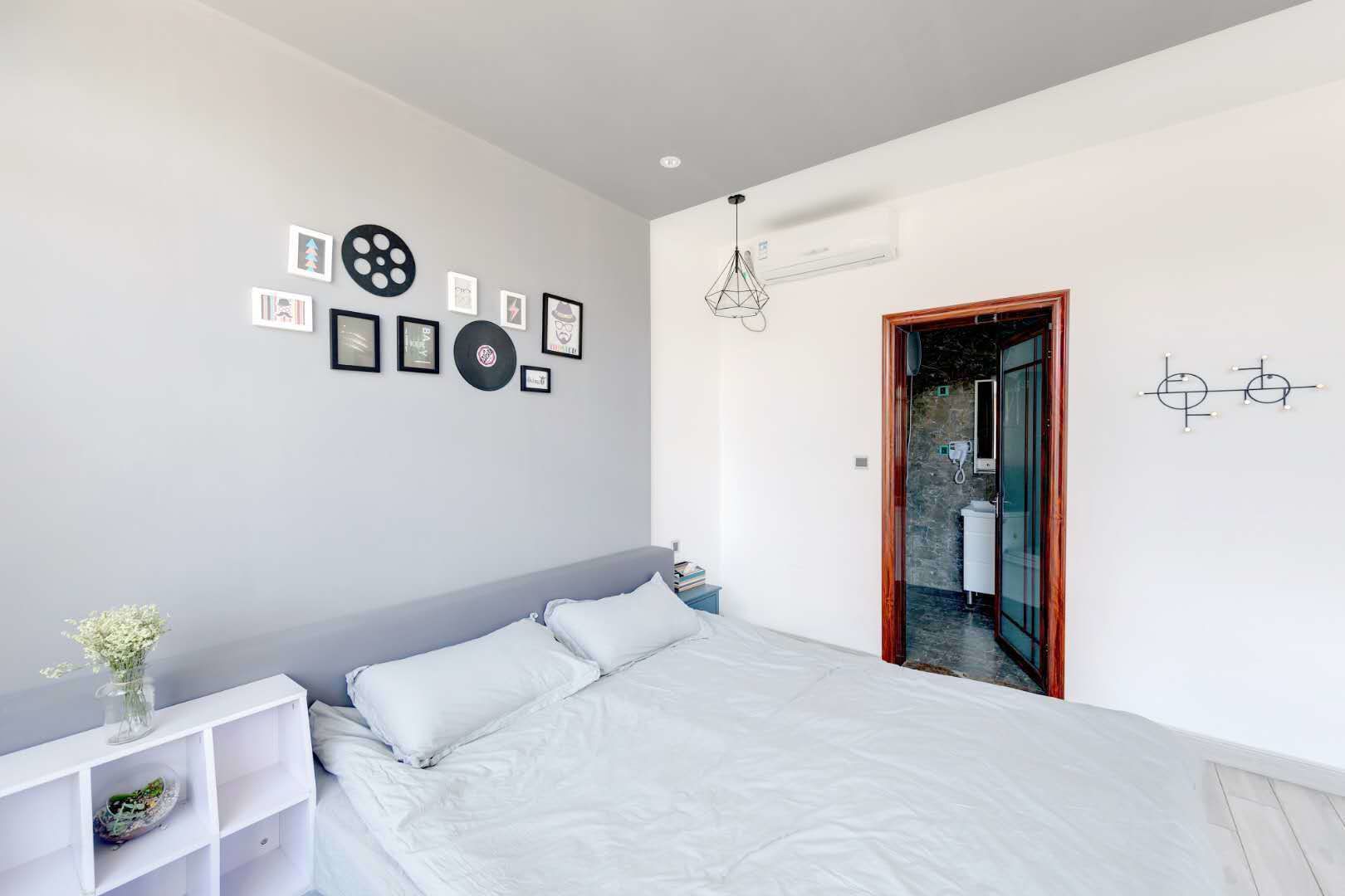 Una camera da letto moderna con un letto grande, un comodino bianco e un condizionatore d'aria a parete.