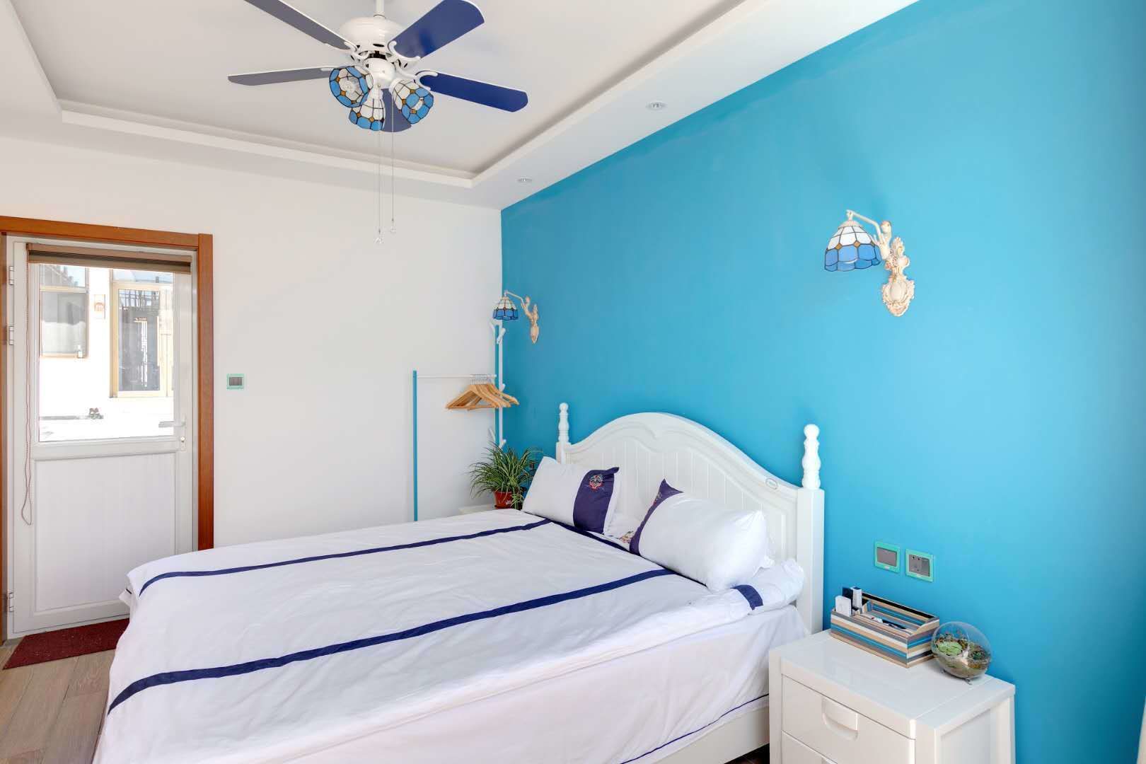 A bedroom with a bed, a nightstand, a ceiling fan, and a window.