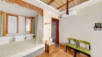 Un dormitorio con cama, una mesita con hervidor y una silla.