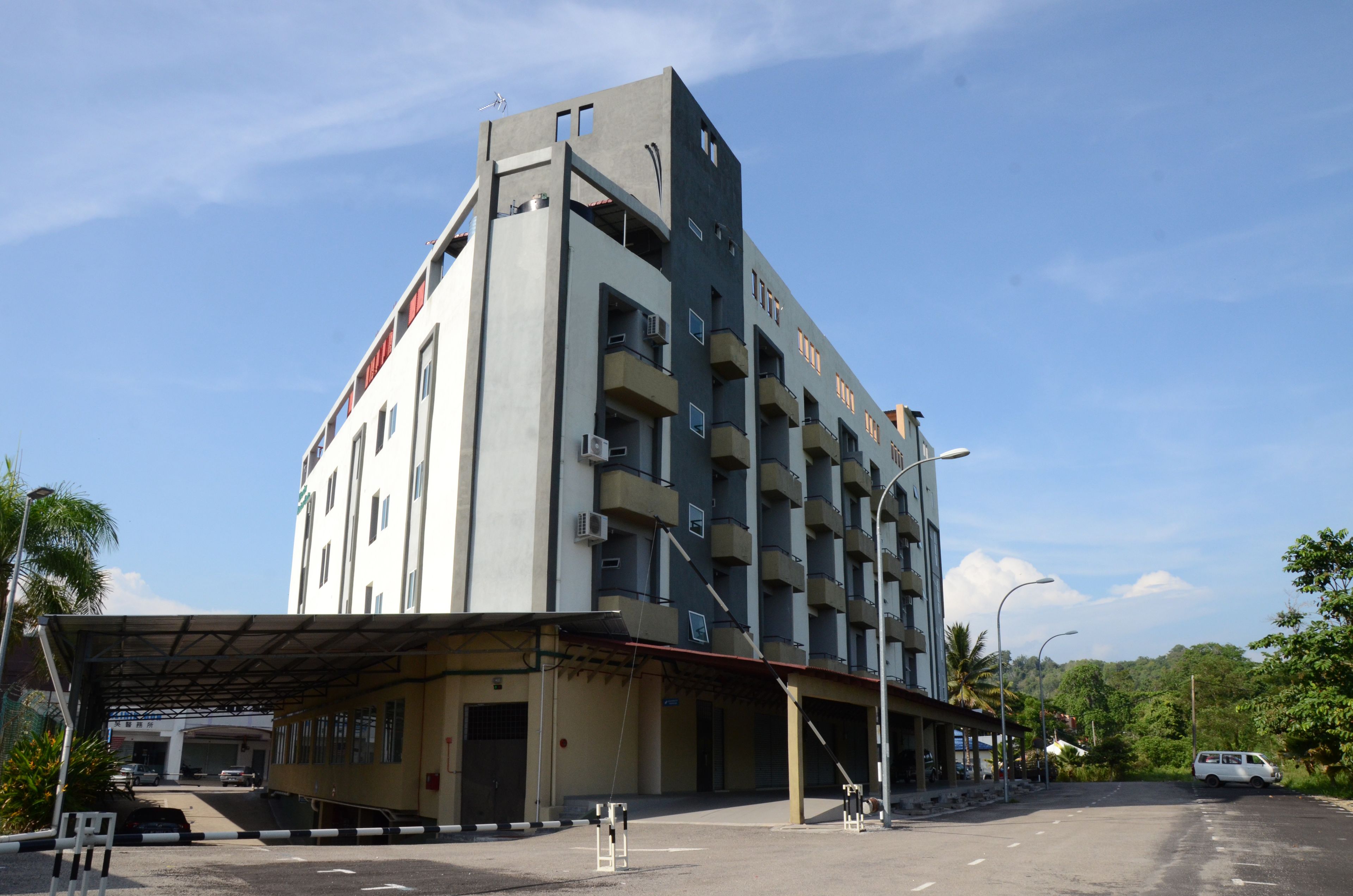 Un immeuble à plusieurs étages, doté d’un toit plat et d’un espace d’entrée abrité.