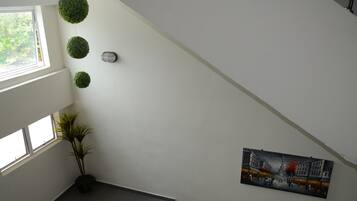 A staircase with a view of the outdoors, a potted plant, and a painting on the wall.