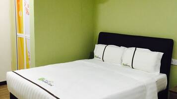 A neatly made bed in a room with a green wall, a painting of a tree, and an air conditioning unit above it.