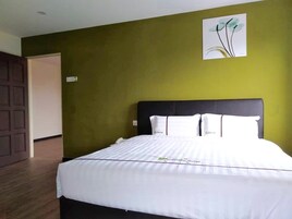 Una habitación de hotel con una cama grande, paredes verdes y una puerta a la izquierda.