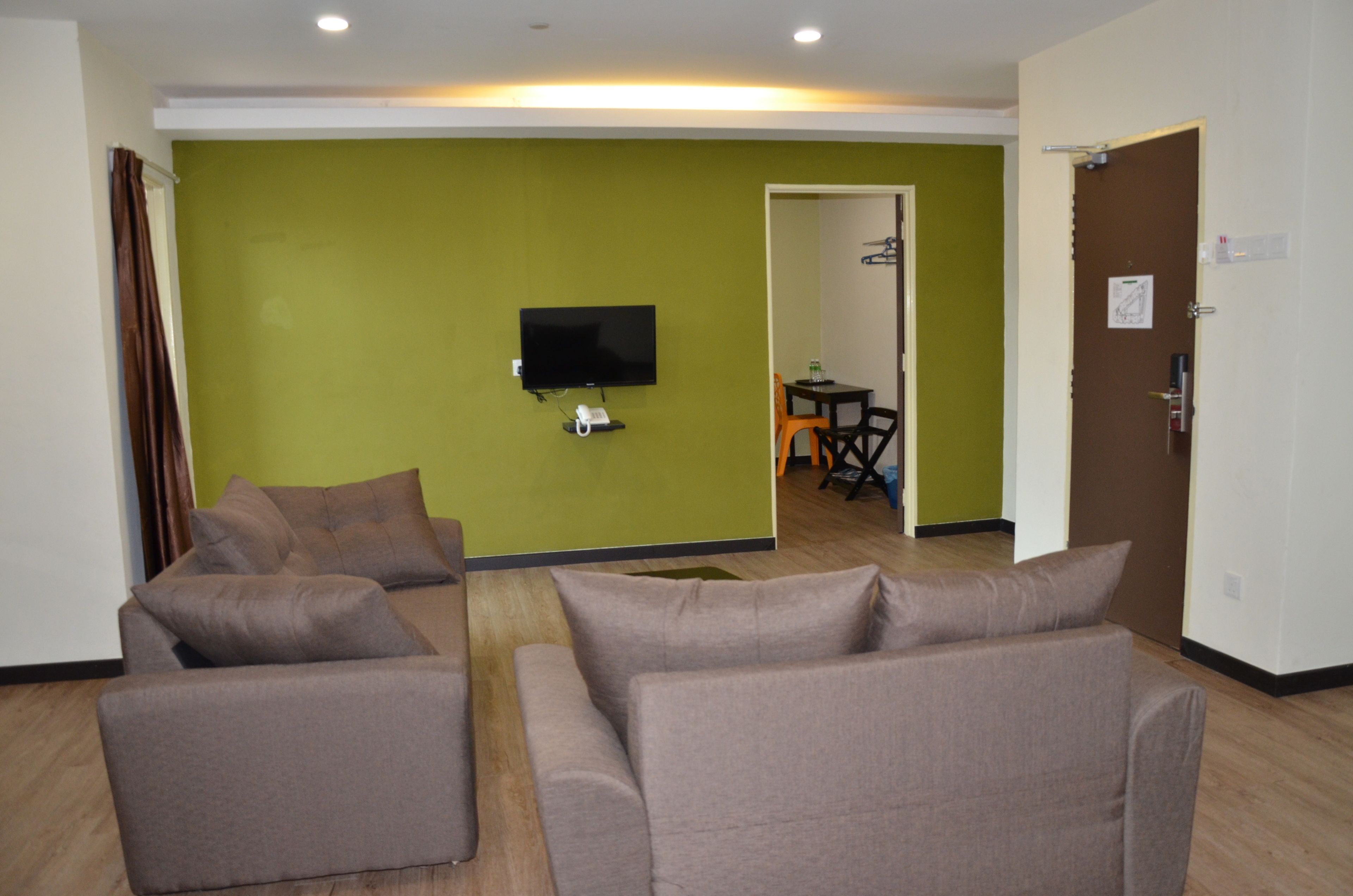 A living room with two sofas, a flat-screen TV, and a green accent wall.