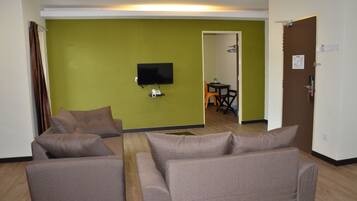 A living room with two sofas, a flat-screen TV, and a green accent wall.