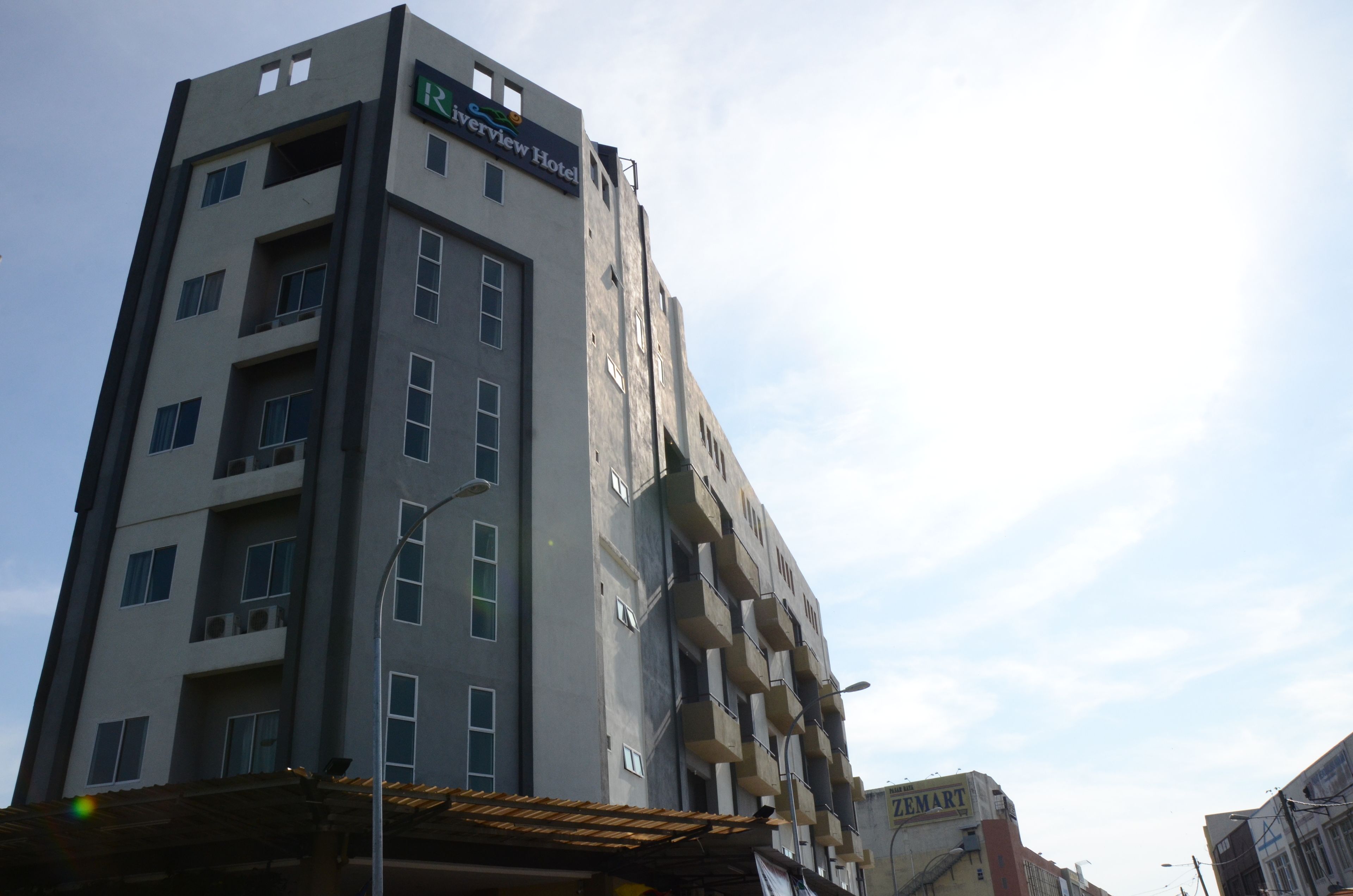 A multi-story hotel with a modern design, featuring balconies and a prominent sign for the Riverview Hotel.