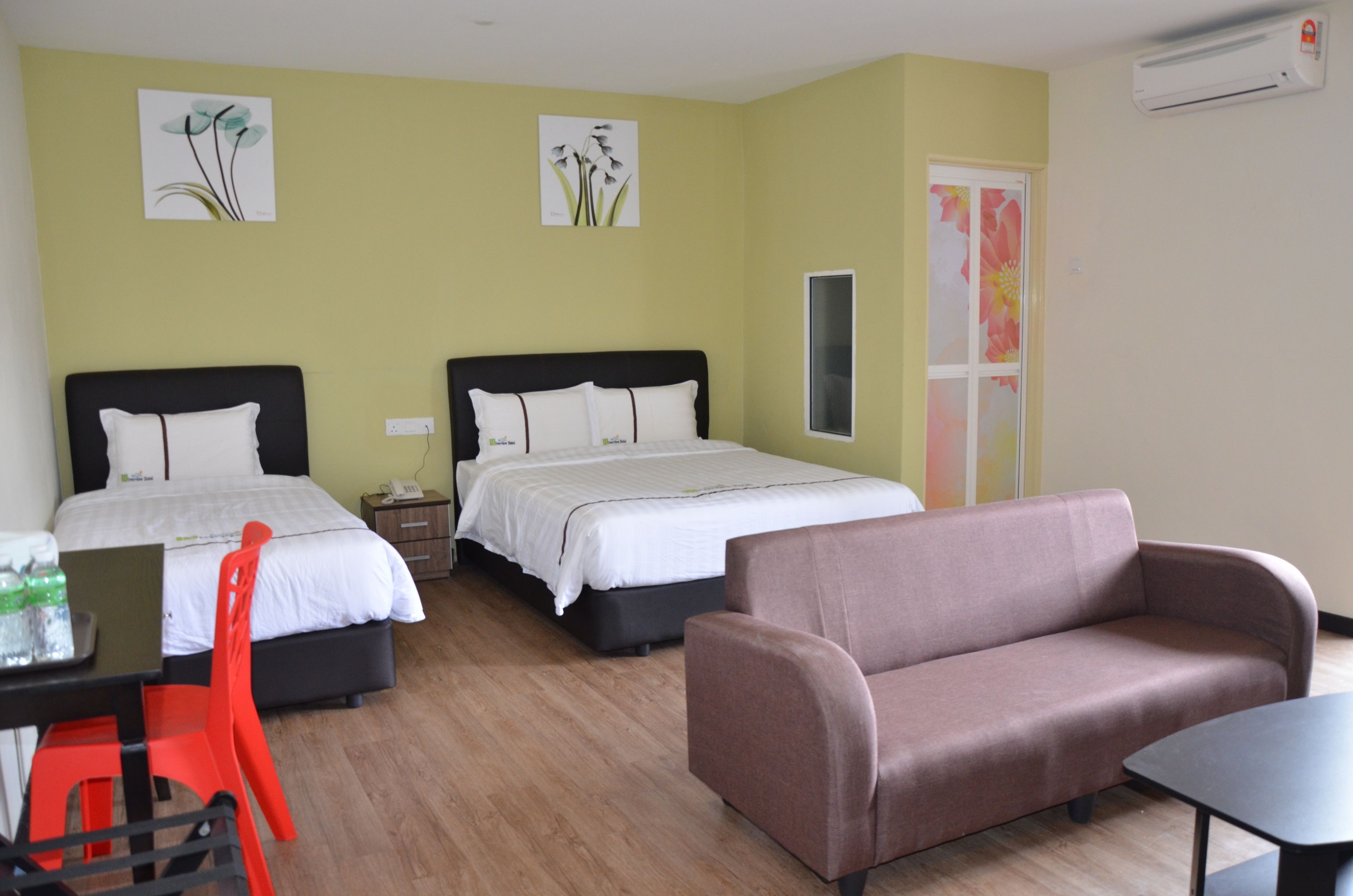 A hotel room with two beds, a sofa, a dining table with chairs, and artwork on the walls.