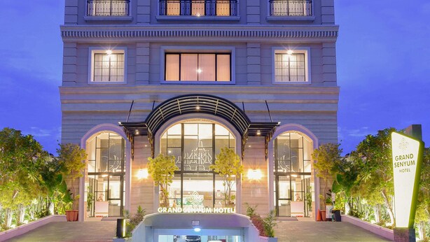 A grand hotel with a symmetrical facade, large windows, and a central entrance. - Grand Senyum Hotel (Yogyakarta)