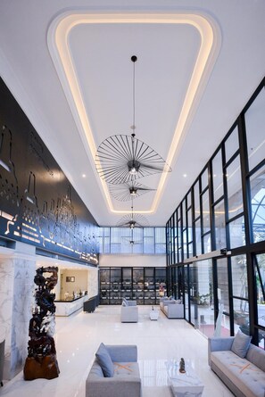 Experience the hotel's inviting lobby with a unique light fixture, comfortable seating areas, and a reception desk.