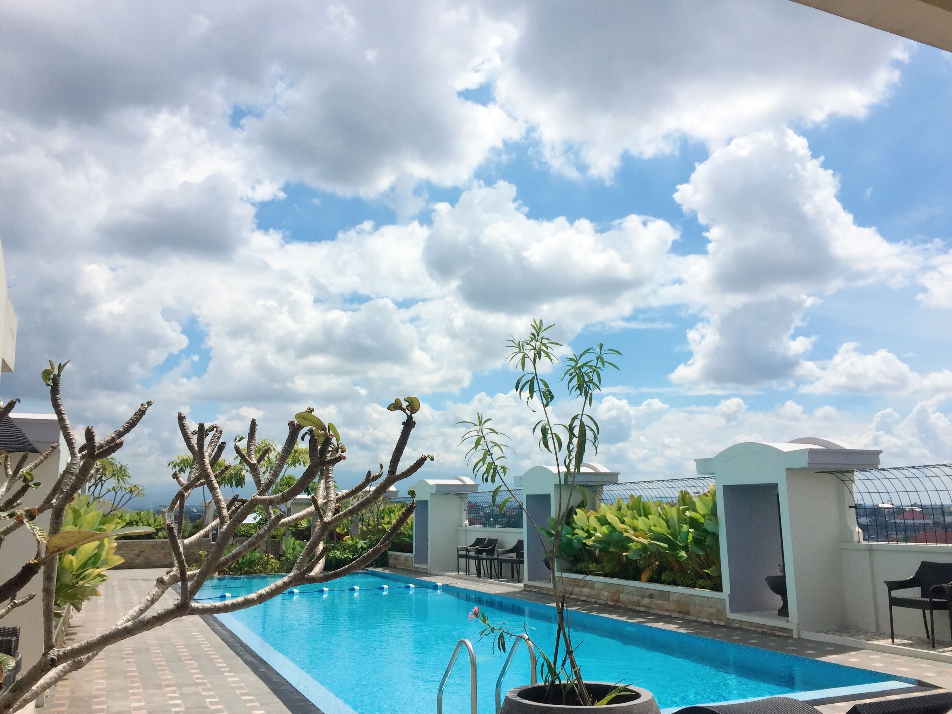 A swimming pool with a clear blue sky and clouds in the background.